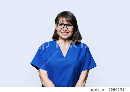 Smiling woman in blue scrubs uniform looking at camera on white background Smiling woman in blue scrubs uniform looking at camera on white background 96662514