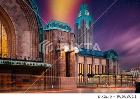 Helsinki, Finland. Very Peri Starry Sky Above Statues On Entrance To Helsinki Central Railway Station. Evening Or Night Illumination. Light Violet Colors. Bright Dramatic Yellow Light Purple Sky 96663611