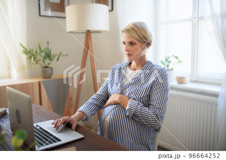 Happy pregnant woman having homeoffice in her living room. Happy pregnant woman having homeoffice in her living room. 96664252