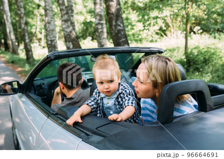 Mom, dad and little son in a convertible car. Summer family road trip to nature 96664691