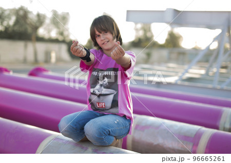 Cute caucasian boy posing in a pink stylish printed t-shirt among pink iron pipes on an industrial background. Fashion style photoshoot Cute caucasian boy posing in a pink stylish printed t-shirt among pink iron pipes on an industrial background. Fashion style photoshoot 96665261
