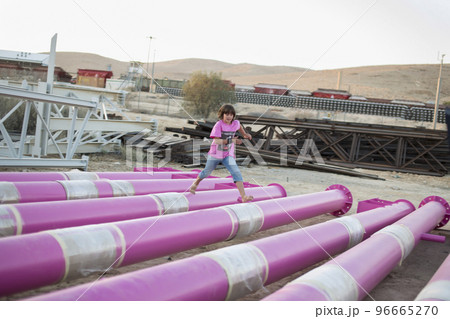 Cute caucasian boy posing in a pink stylish printed t-shirt among pink iron pipes on an industrial background. Fashion style photoshoot Cute caucasian boy posing in a pink stylish printed t-shirt among pink iron pipes on an industrial background. Fashion style photoshoot 96665270
