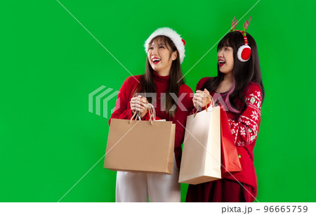 Young asian woman in red and white color Christmas theme costume wearing santa hat surprised when open shopping bag Young asian woman in red and white color Christmas theme costume wearing santa hat surprised when open shopping bag 96665759