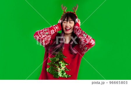 Asian woman long hairstyle wear red sweater happy face listenting to music on green screen background. Merry Christmas concept. 96665803