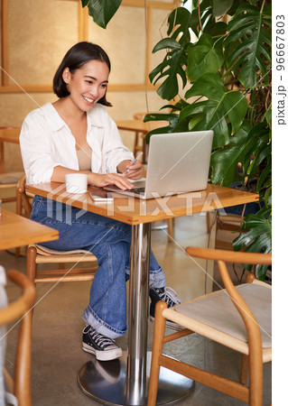 Stylish businesswoman with laptop, sitting in cafe and working on computer, managing business and drinking coffee 96667803
