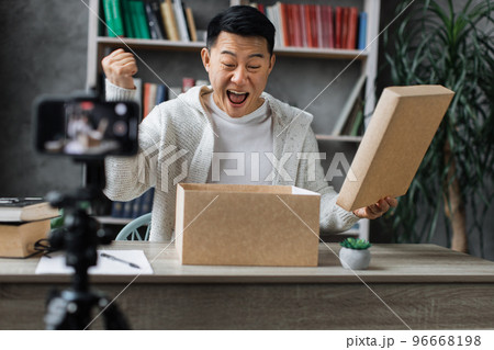 Happy asian male blogger unpacking gift boxes presents from companies and doing live streaming. Happy asian male blogger unpacking gift boxes presents from companies and doing live streaming. 96668198
