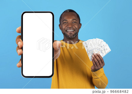 Cheerful rich black man showing smartphone blank screen and cash 96668482