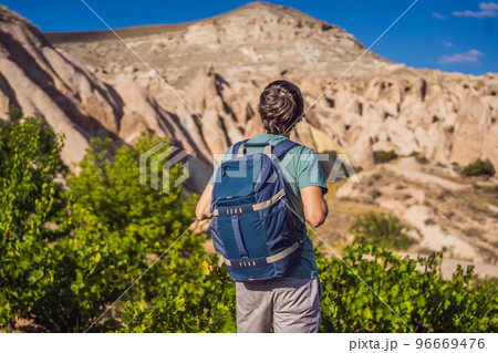 Young man exploring valley with rock formations and fairy caves near Goreme in Cappadocia Turkey Young man exploring valley with rock formations and fairy caves near Goreme in Cappadocia Turkey 96669476