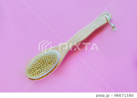Brush with a handle for dry anti-cellulite massage or brushing on pink background. Beauty concept 96671380