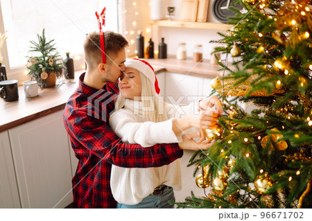 Happy couple decorating christmas tree at home. Smiling Man and Woman together Celebrating Christmas Happy couple decorating christmas tree at home. Smiling Man and Woman together Celebrating Christmas 96671702