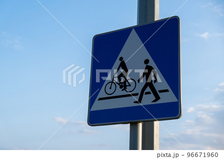 Cyclist and pedestrian route sharing sign. Road sign Pedestrian and bicycle can cross the street here on the background of blue sky Cyclist and pedestrian route sharing sign. Road sign Pedestrian and bicycle can cross the street here on the background of blue sky 96671960