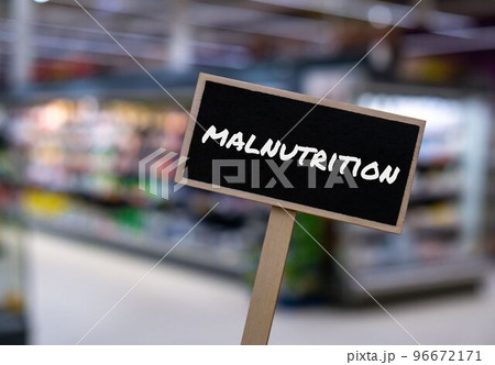 Wooden information label sign with text MALNUTRITION against defocused store shelves message. Global hunger, inflation, high prices, increasing living expenses and poverty, financial crisis, food Wooden information label sign with text MALNUTRITION against defocused store shelves message. Global hunger, inflation, high prices, increasing living expenses and poverty, financial crisis, food 96672171