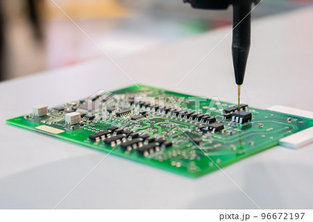 Automatic manipulator with dispenser needle during work with SMT pcb - close up Automatic manipulator with dispenser needle during work with SMT pcb - close up 96672197