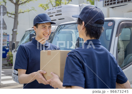 担当地域の配達員に荷物を渡す同僚 96673245