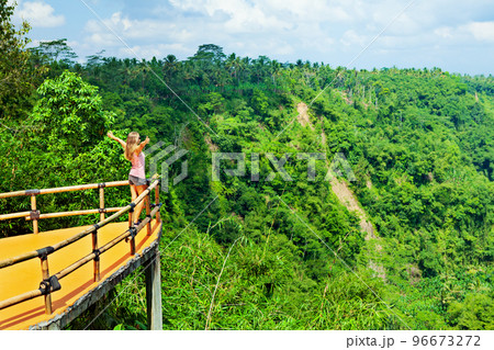 Woman stand at balcony on high cliff with jungle view 96673272