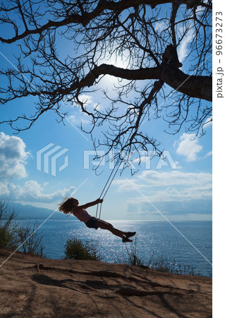 Happy girl have fun swinging high in mid air 96673273