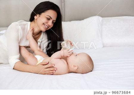 happy mother feeding her newborn baby on the bed 96673684