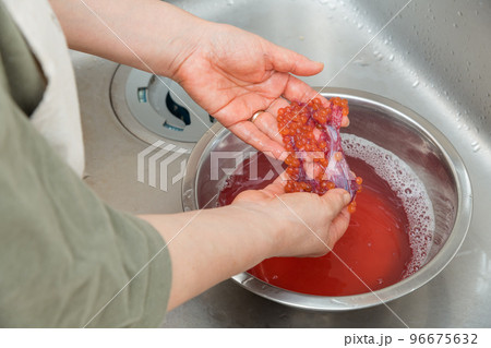【イクラの醤油漬けを作るために、塩を入れたぬるま湯に生イクラを入れほぐす】 96675632