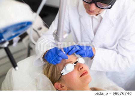 Woman getting laser facial treatment in aesthetic medicine office 96676740
