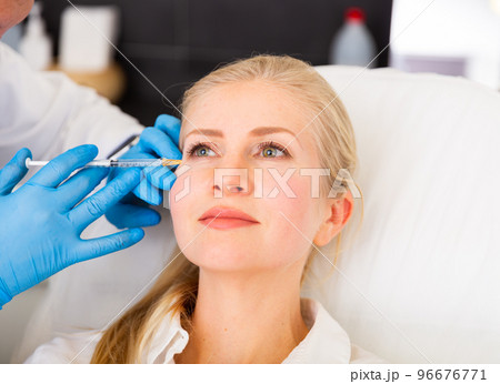 Cosmetologist doing botulotoxin injections for young woman 96676771