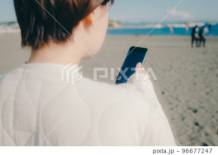 海岸でスマホを持つ女性の写真 海岸でスマホを持つ女性の写真 96677247
