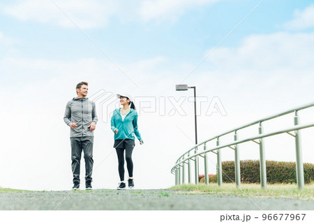 公園で景色を見ながらウォーキングするスポーツウェアを着た男女（夫婦・カップル） 96677967