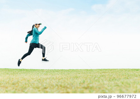草原をジャンプしながら走るスポーツウェアのアジア人女性 96677972