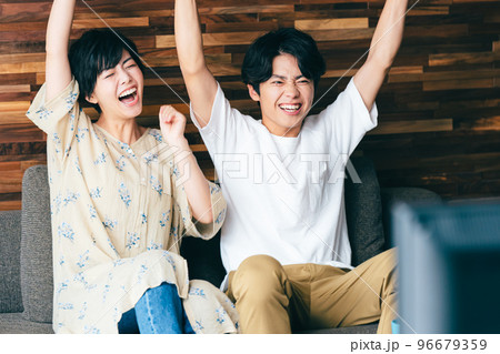 テレビを見ながら喜びを分かち合うカップル 96679359