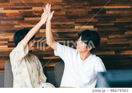 テレビを見ながら喜びを分かち合うカップル 96679362