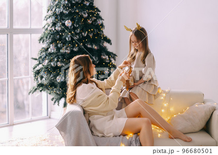 Mom and daughter on the couch opening a gift Mom and daughter on the couch opening a gift 96680501