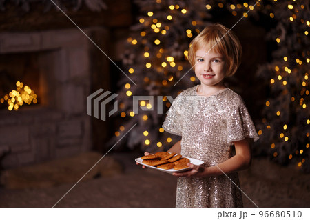 The girl is holding a plate of cookies. 96680510