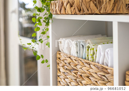 Neatly folded linen cupboard shelves storage at eco friendly straw basket placed closet organizer 96681052