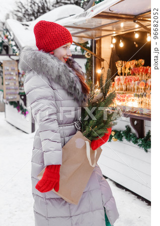 A bright woman in winter clothes walks around the city decorated for Christmas. Lifestyle in the winter season 96682052