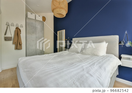 Comfortable bed covered with blanket and located in light bedroom of modern apartment Comfortable bed covered with blanket and located in light bedroom of modern apartment 96682542