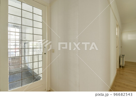 Light narrow hallway with many doors in white walls and glowing lamp over lumber floor 96682543