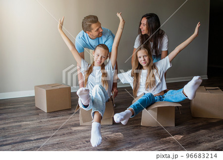 Happy family with two daughters have fun in their new home. Parent with kids enjoy their moving day 96683214
