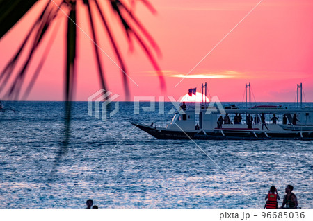 Boracay, Philippines - Jan 21, 2020: Sunset on the background of bottles standing on the bar. The sun passes through the bright glass of the bottles. Background image for the screensaver. 96685036