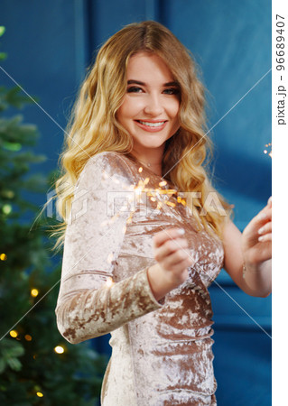 a beautiful woman with sparklers in a blue room with a Christmas tree. 96689407