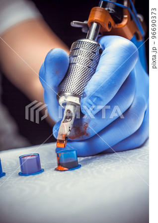 Tattooer's hand and a tattoo machine. 96690373