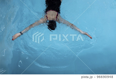 Young swimmer wears a swim cap and puts away goggles Young swimmer wears a swim cap and puts away goggles 96690948