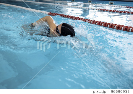 Young swimmer wears a swim cap and puts away goggles Young swimmer wears a swim cap and puts away goggles 96690952