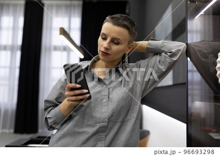 caucasian woman with short haircut holding phone 96693298