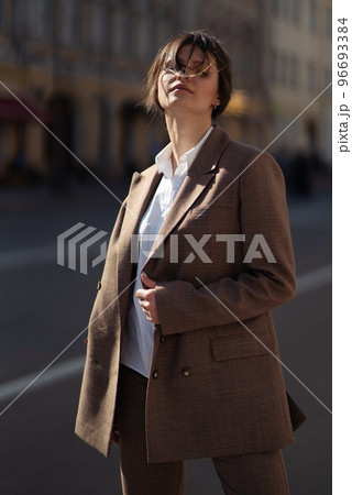 High fashion portrait of young elegant woman in brown suit walk on the street. enjoy summer lights. 96693384