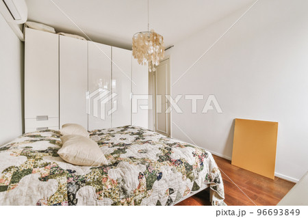 Home interior design of bedroom with bed and wooden wardrobe placed in corner near window in modern apartment 96693849