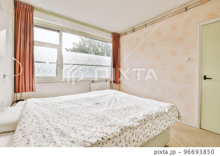Home interior design of bedroom with bed and wooden wardrobe placed in corner near window in modern apartment 96693850