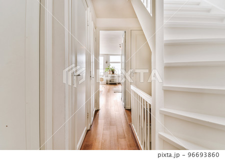 White hallway with wooden stairway leading to second floor of modern luxury apartment with minimalist interior design 96693860