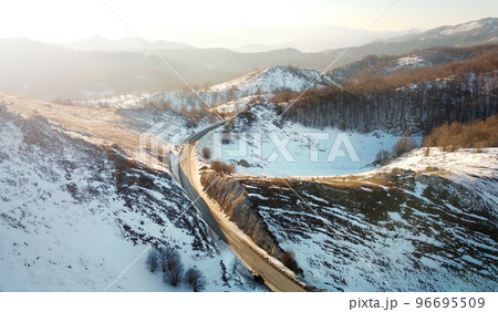 Amazing sunset aerial top drone view of high-speed road between the picturesque mountains in winter. Top down view of picturesque mountain serpentine stretching into the distance. 96695509