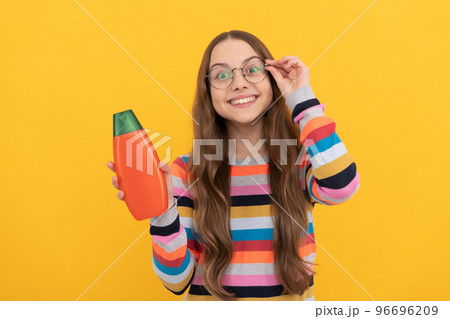 cheerful child long hair in glasses presenting shampoo bottle, advertisement cheerful child long hair in glasses presenting shampoo bottle, advertisement 96696209