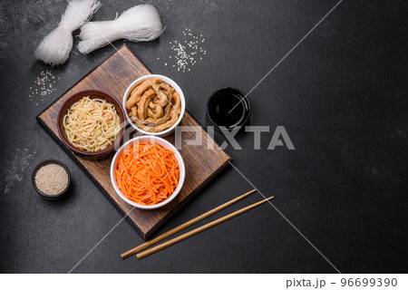 Tasty spicy Korean carrot with spices and herbs on a dark concrete background 96699390