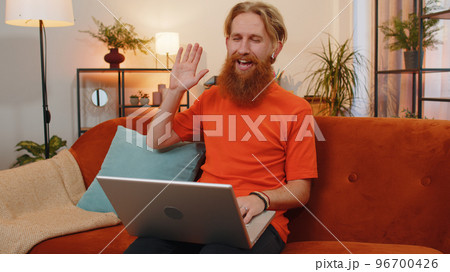 Man sitting on home couch, looking at camera, making video conference call with friends or family 96700426